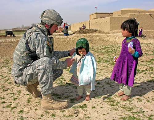 Maj. Michael McCusker distributes winter clothing to Hazaras children during his 2005-2006 deployment to northern Afghanistan with the U.S. Army. 