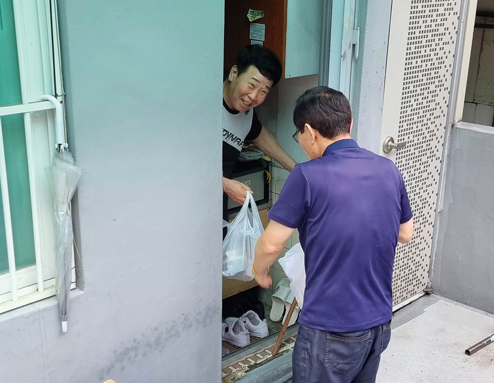 A man receives a meal from Choi Kumwook, a member of St. Peter Yi Ho-yong Council 17799 in Bucheon, South Korea. Every Thursday, council members deliver meals to community members in need.