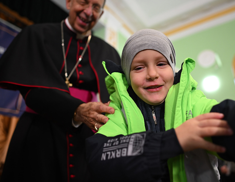 Archbishop Lori helps put a new coat on a child during a Coats for Kids distribution near Bucha, Ukraine, Oct. 19. (Photo by Andrii Gorb)