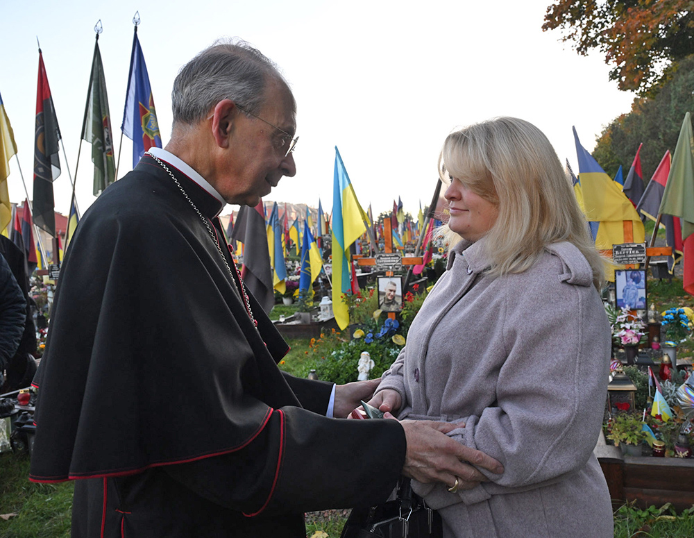 Archbishop Lori speaks to Olha Vorobyova after praying next to the grave for her deceased husband, who was a Knight, at the Field of Mars military cemetery in Lviv, Ukraine, Oct. 21. (Photo by Andrii Gorb)