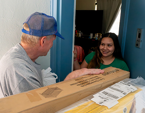 A young woman opens the door to a new crib from Project Manger. (Photo by Matthew Barrick)