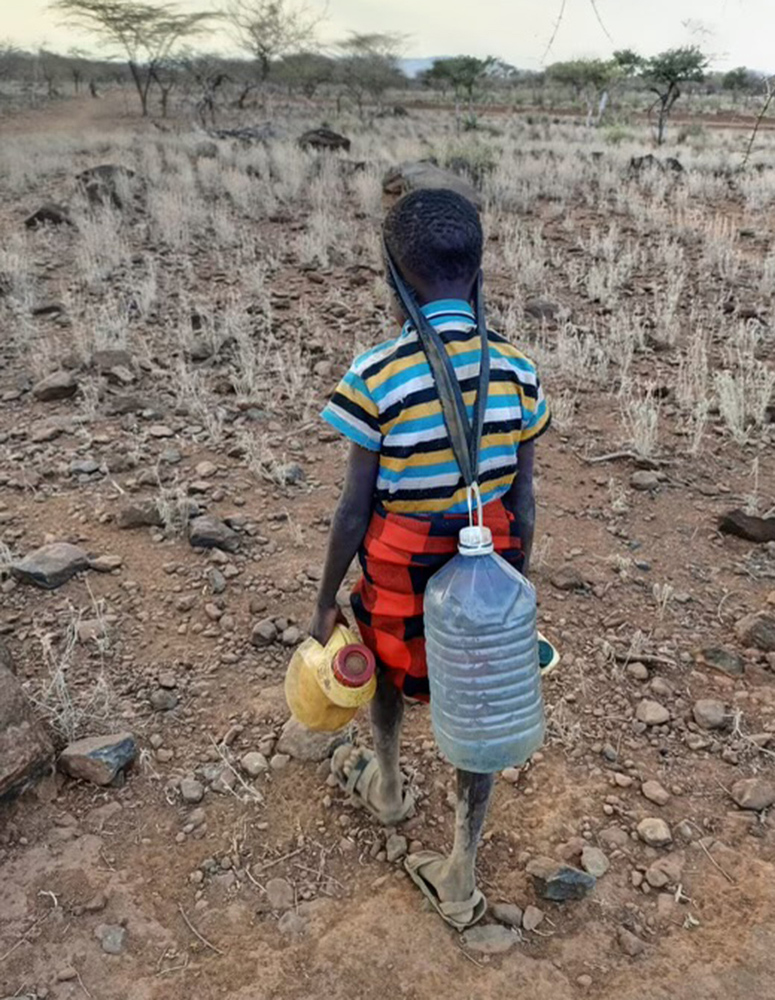 A little girl carries several jugs of water outside the village of Kambai, Kenya. (Courtesy of Father Cosmus Wambua)