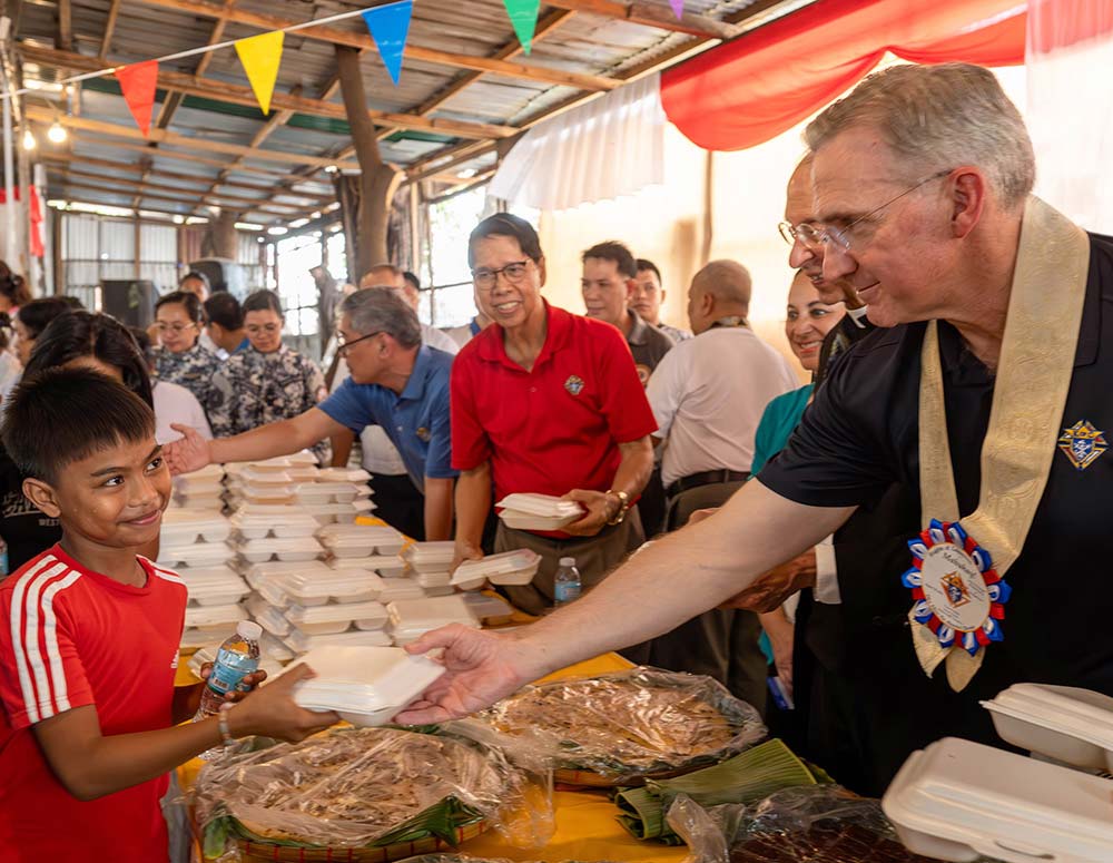 Supreme Knight Patrick Kelly assists with the food distribution program at Santo Niño de Baseco Parish in Manila on Aug. 20. Pictured center, in red, is Supreme Director Rene Sarmiento, a former Luzon North deputy.