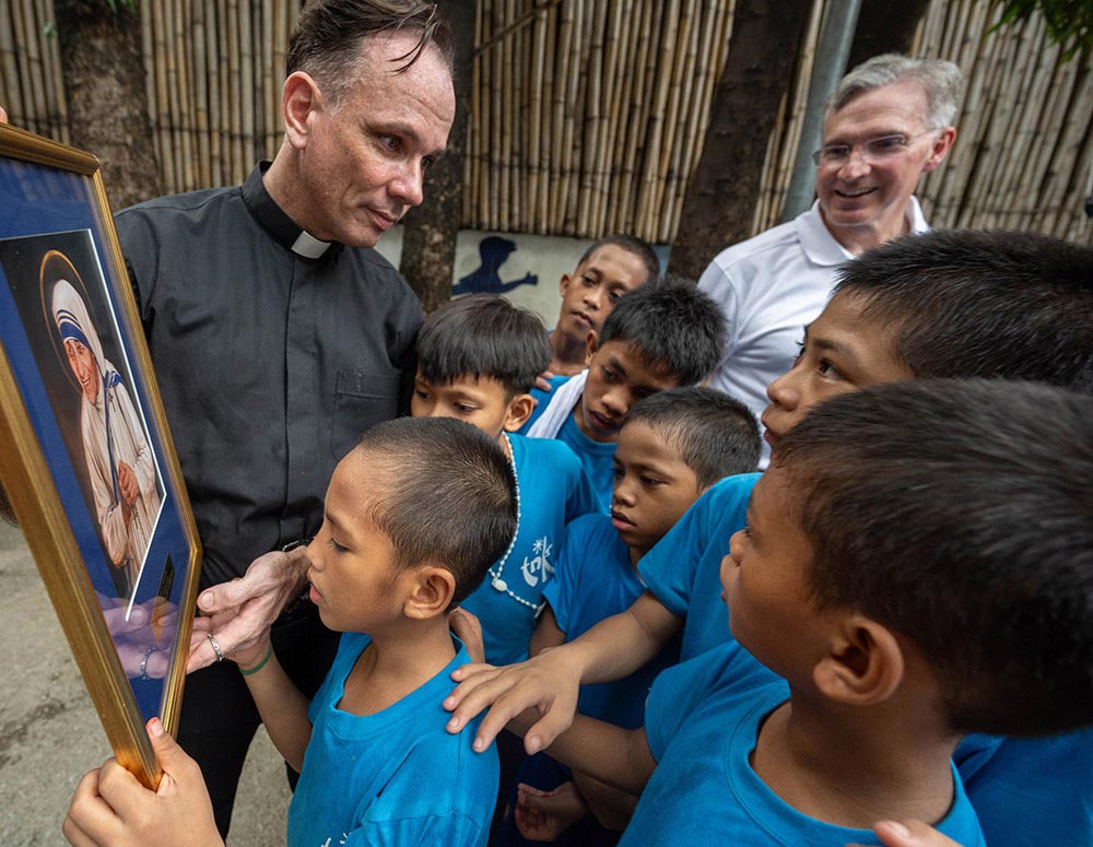 Father Matthieu Dauchez displays a framed image of Mother Teresa presented by Supreme Knight Patrick Kelly to children from the foundation’s Bridge Class Program. The portrait, painted by Chas Fagan, was commissioned by the Knights of Columbus and was used as Mother Teresa’s canonization image. (Photo by Tamino Petelinšek)