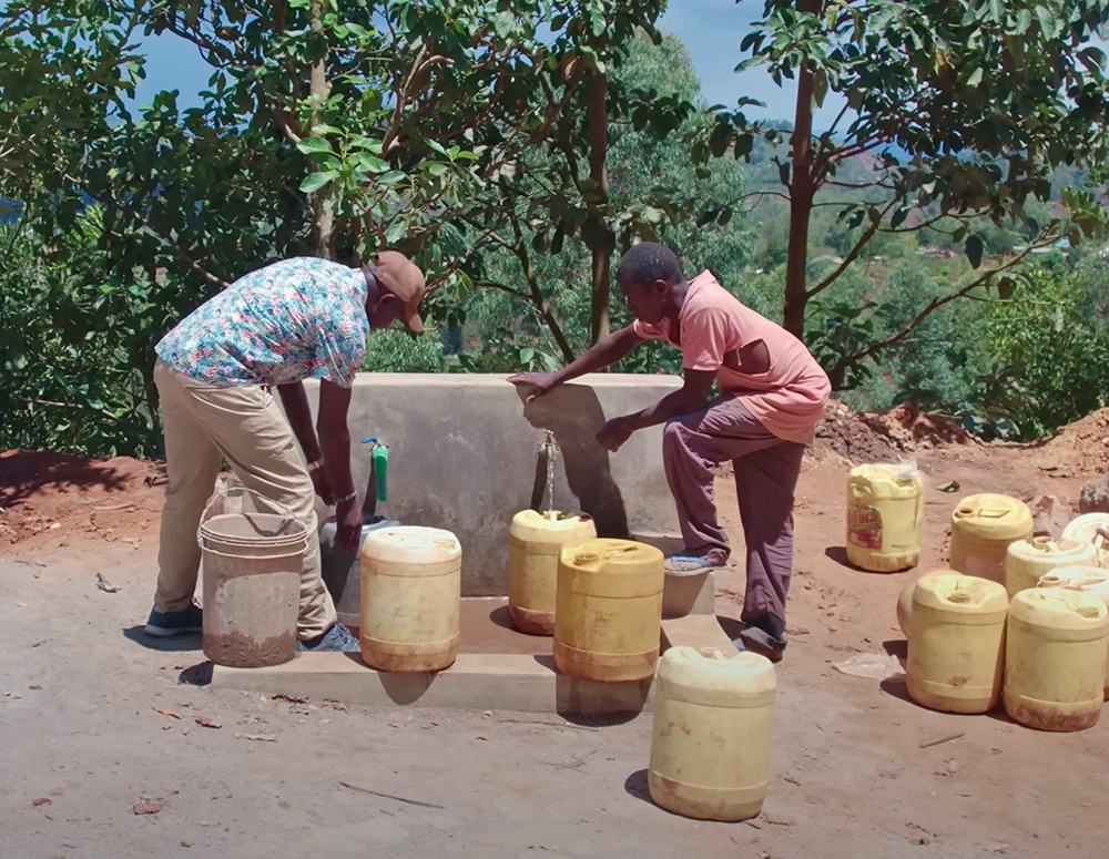 Men fill containers with water from the new well in Kambai, Kenya, inspired by Father Cosmus Wambua and sponsored by Our Lady Star of the Sea Council 7122 in North Myrtle Beach, S.C. (Castletown Media)