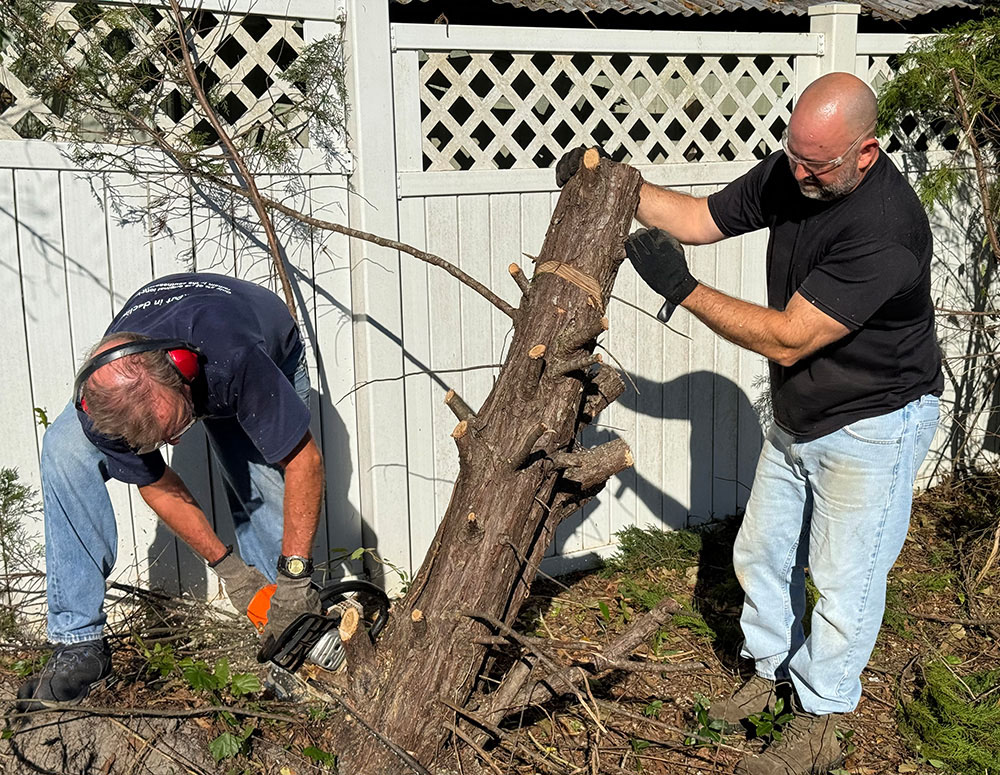 Ed Wonn (left) of Father Clement Borschers Council 8568 in Vidalia, Ga., and Danny Walters of Father Michael A. Burke Council 14488 in Kathleen cut down a damaged tree outside the home of an elderly parishioner of Sacred Heart Catholic Church. A team from Council 14488 traveled to Vidalia in early October to help local Knights clear debris for neighbors in need. (Photo courtesy of Kevin Schneider)