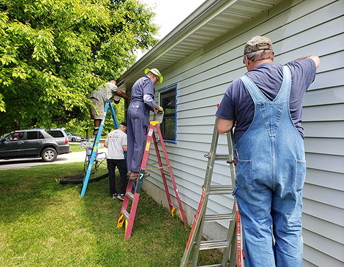 Knights from Indiana and Michigan paint a house at Sharing Meadows in La Porte, Ind., during a service weekend organized by Council 9114 last summer. (Courtesy of Mike Catania)