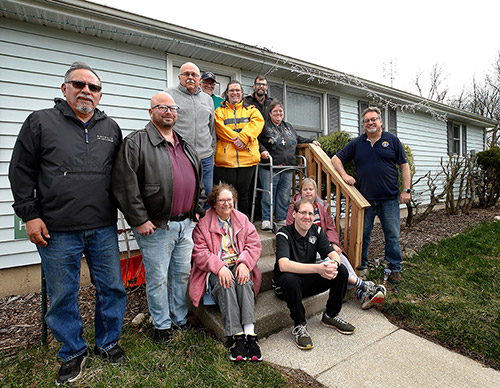 Members of Council 9114 gather with Sharing Meadows residents outside one of the houses they painted last summer. (Photo by Karen Callaway)