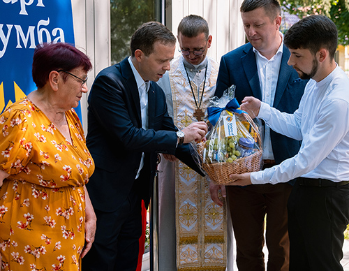 From left, a resident receives a gift from Szymon Czyszek, the Order’s director of international growth in Europe; Father Volodymyr Malchyn; and Ukraine State Deputy Mykola Mostovyak. (Photo by Ihor Ivanovych)