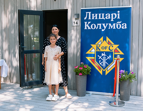 A mother stands with her child outside their new home after it was blessed July 12. (Photo by Ihor Ivanovych)