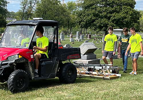 Students from the High School of St. Thomas More drive a utility terrain vehicle pulling radar equipment through St. Mary’s Cemetery on Sept. 9.