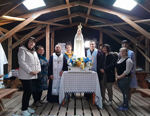 Parishioners gather around Father Bohomaz and the image of Our Lady of Fatima during his visit to the newly formed Parish of the Nativity of the Most Holy Theotokos (Mother of God) in Chumaky village, Dnipropetrovsk region, in October 2023.