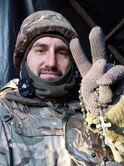 Denys Tarasov, a member of God the Merciful Father Council 16460 in Zaporizhzhia, Ukraine, holds up his rosary in a photo taken during his service in the Ukraine Army. 