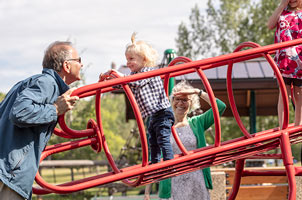 Grandparents in a park playing with their grandchild.